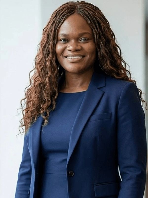Ramona Q Williams, Founder & CEO, smiling warmly in a professional navy blue suit.