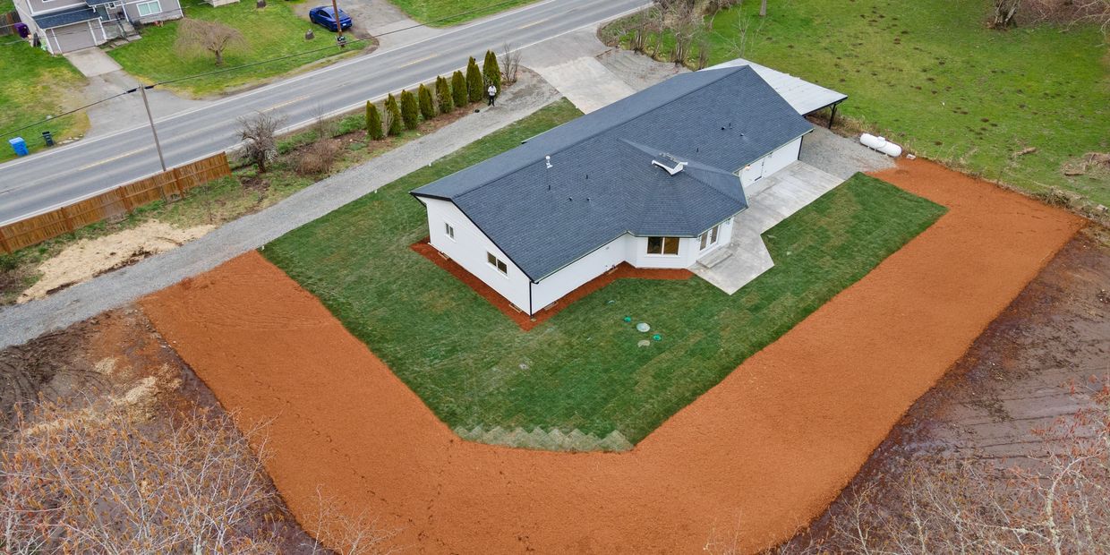 A newly landscaped house with fresh mulch surrounding the green lawn.