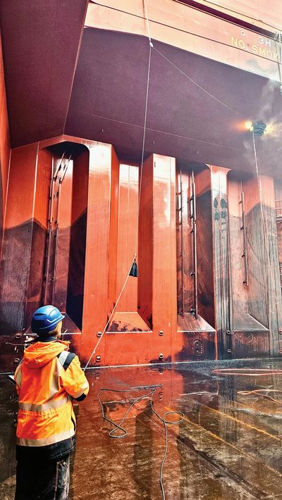 Person in safety gear inspects large industrial metal structure indoors.