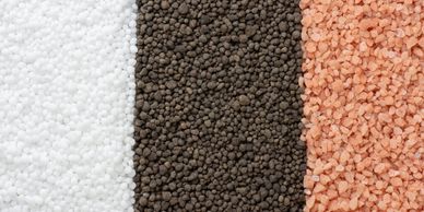 Three vertical piles of different granular materials in white, black, and pink.