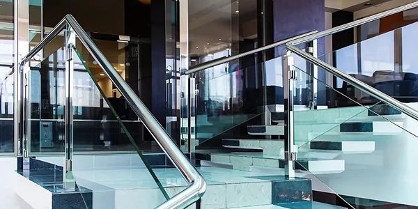 Modern staircase with glass panels and stainless steel handrails in a sleek interior.