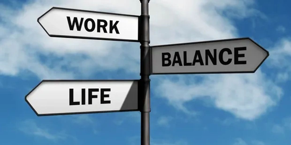 Signpost showing directions for work, life, and balance against a blue sky.