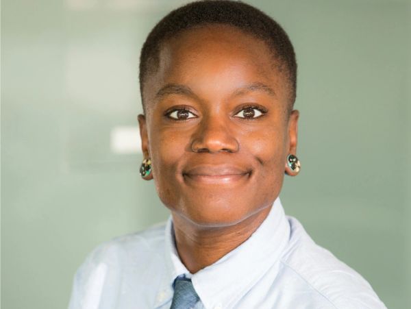 Smiling person with short hair wearing a white shirt and tie.