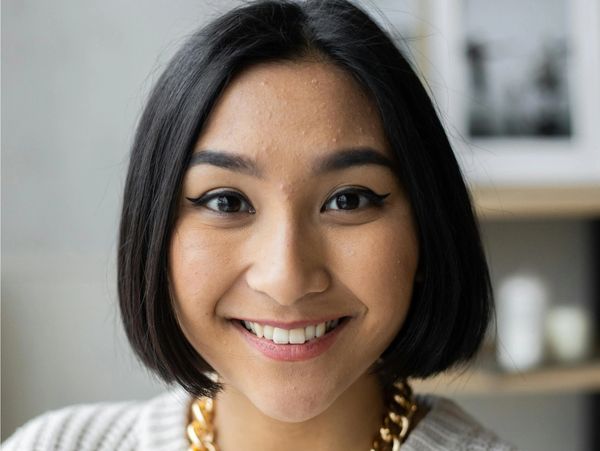 Smiling woman with a bob haircut and gold chain necklace.