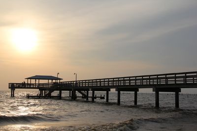 Long wooden pier on the Eastern Shore of Mobile Bay, Alabama, lit by a hazy sunset.