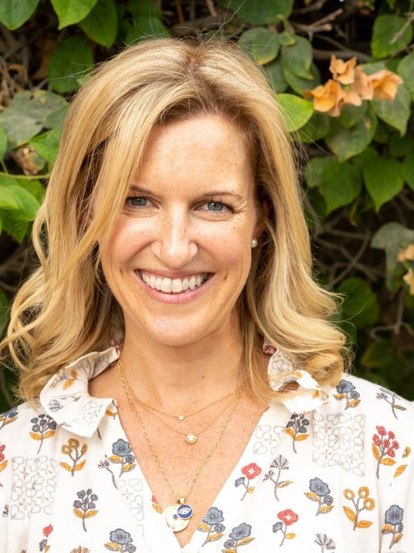 Image of the founder, Jacqueline Perrottet. Happy headshot smiling in front of flowers in the garden.