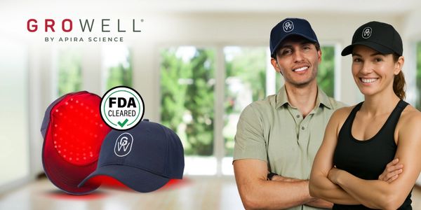 Two smiling people wearing Growell caps with an FDA-cleared red light therapy device.