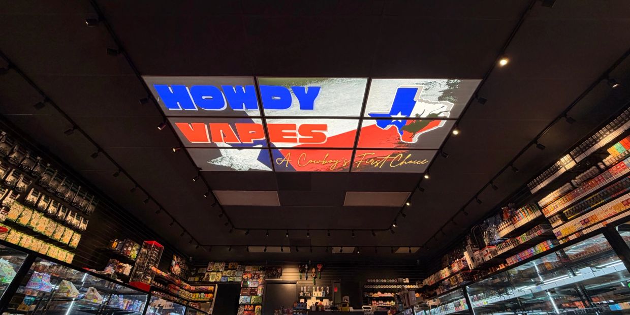 Interior of Howdy Vapes store with illuminated ceiling sign.