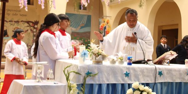 A priest and altar servers conducting a religious ceremony at a decorated altar.