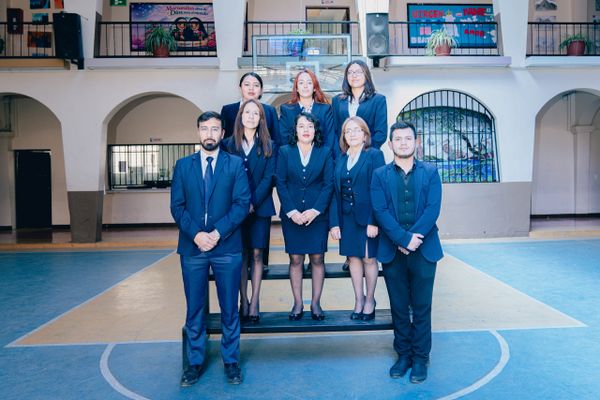 A group of eight professionally dressed individuals posing indoors.