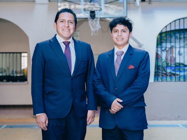 Two men in formal suits posing indoors.