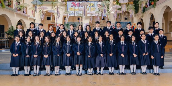 A group photo of students in uniform standing in rows inside a decorated hall.