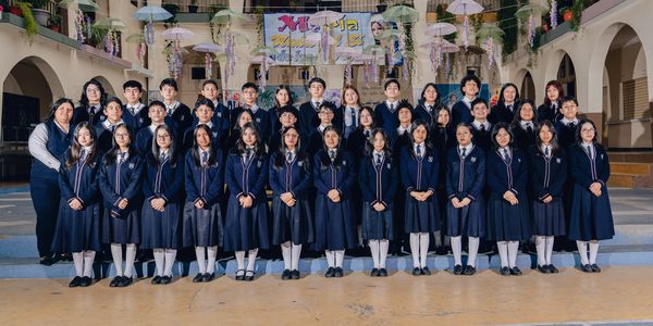 A formal group photo of students in uniforms in a decorated school courtyard.