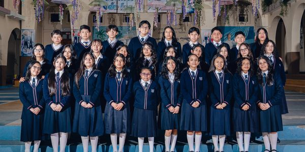 A group of students in school uniforms posing for a formal photo indoors.