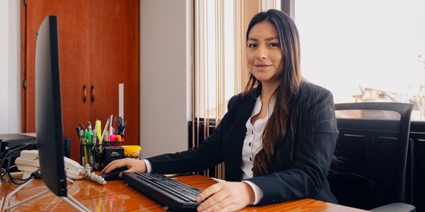 A professional woman working at her desk with a computer in an office.