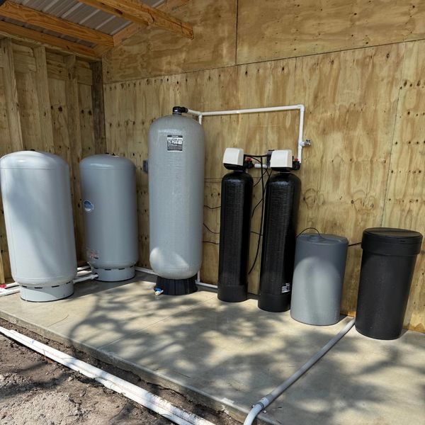 Water filtration and pressure tanks installed on concrete floor.