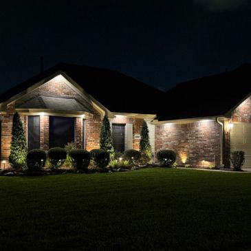 House exterior lit up at night with landscape lighting.
