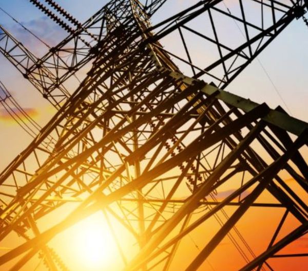Sunset behind an intricate electrical transmission tower structure.