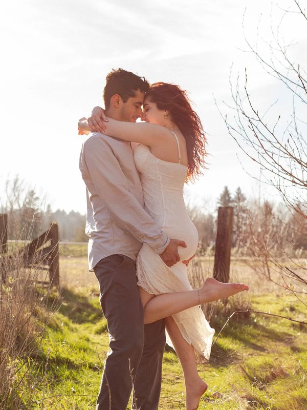 Healthy couple embracing intimately in a sunlit field, sharing a romantic moment.