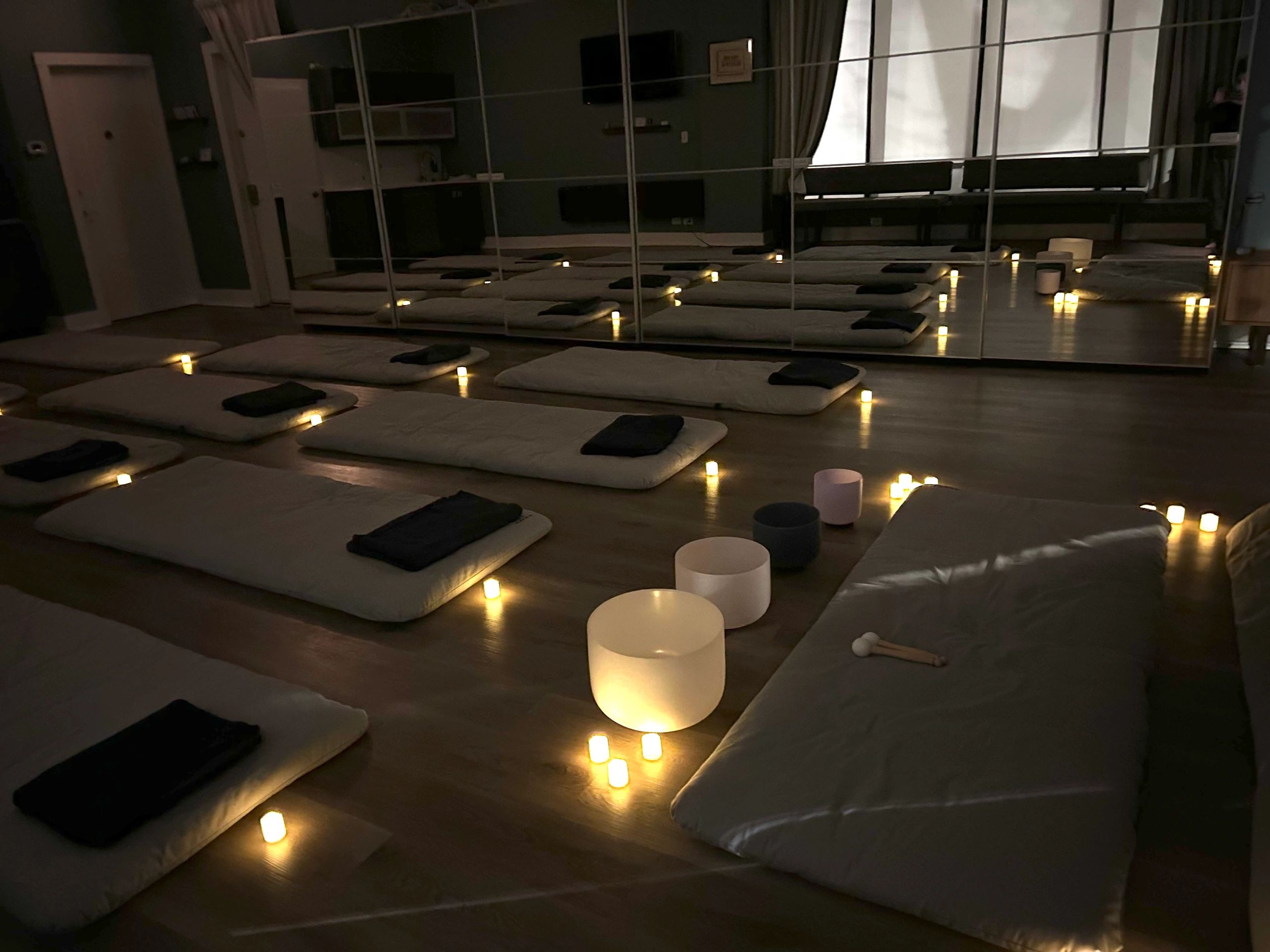 Candlelit sound bath and meditation setup with yoga mats and crystal singing bowls at HippieGirlfriend Wellness in Chicago.