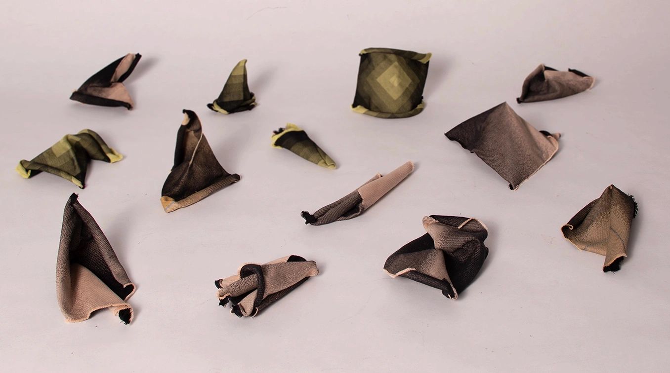 Various small fabric pieces folded into different shapes on a plain surface.