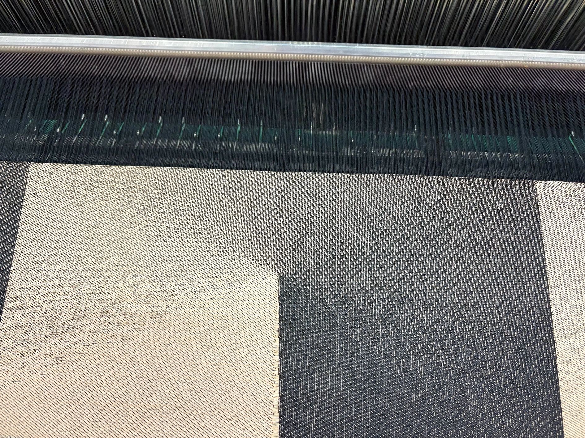 Close-up of a weaving loom with black and white fabric in progress.