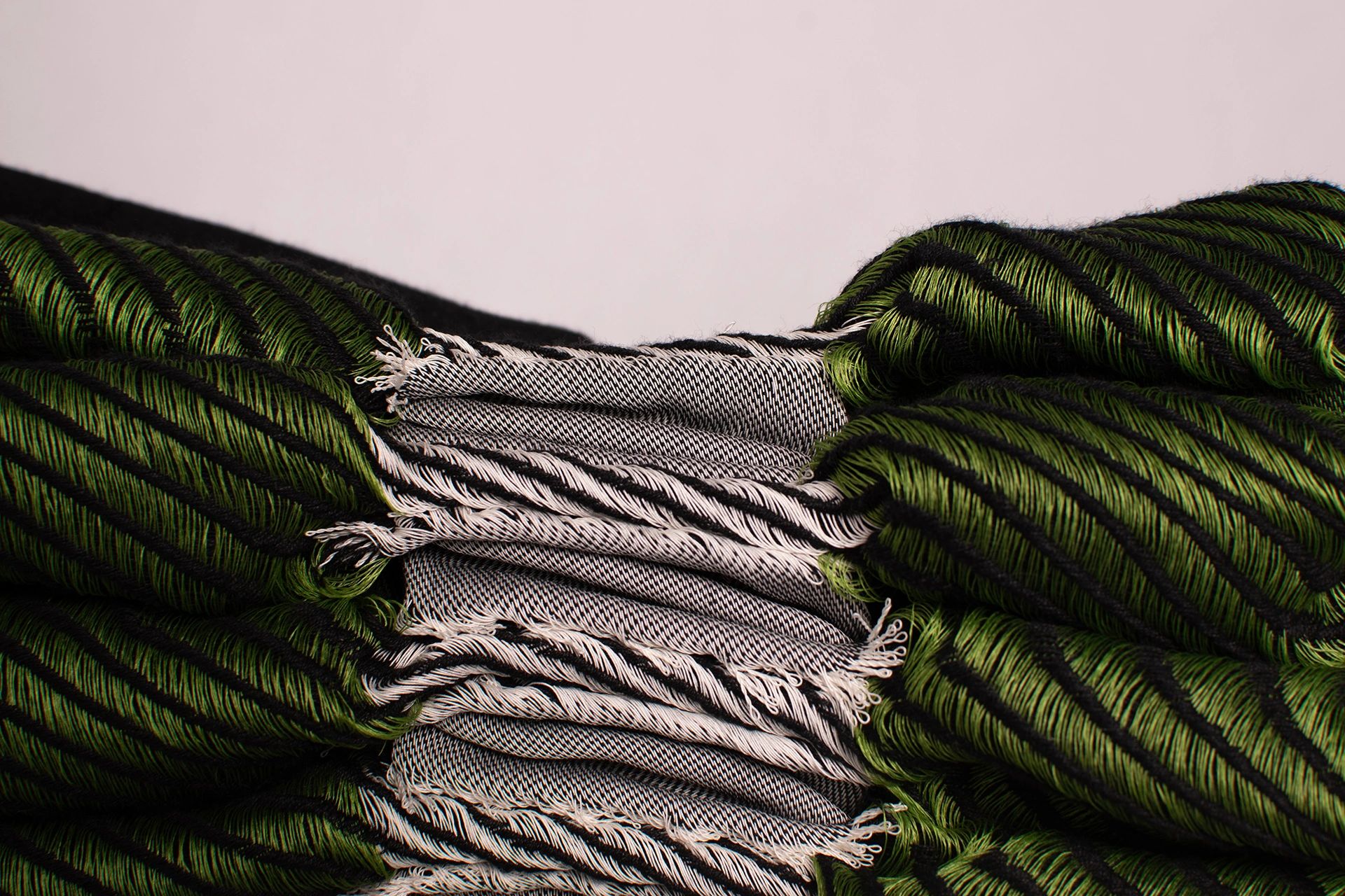 Close-up of a green and black striped woven fabric with fringes.