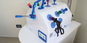 A medical training device with surgical instruments attached.