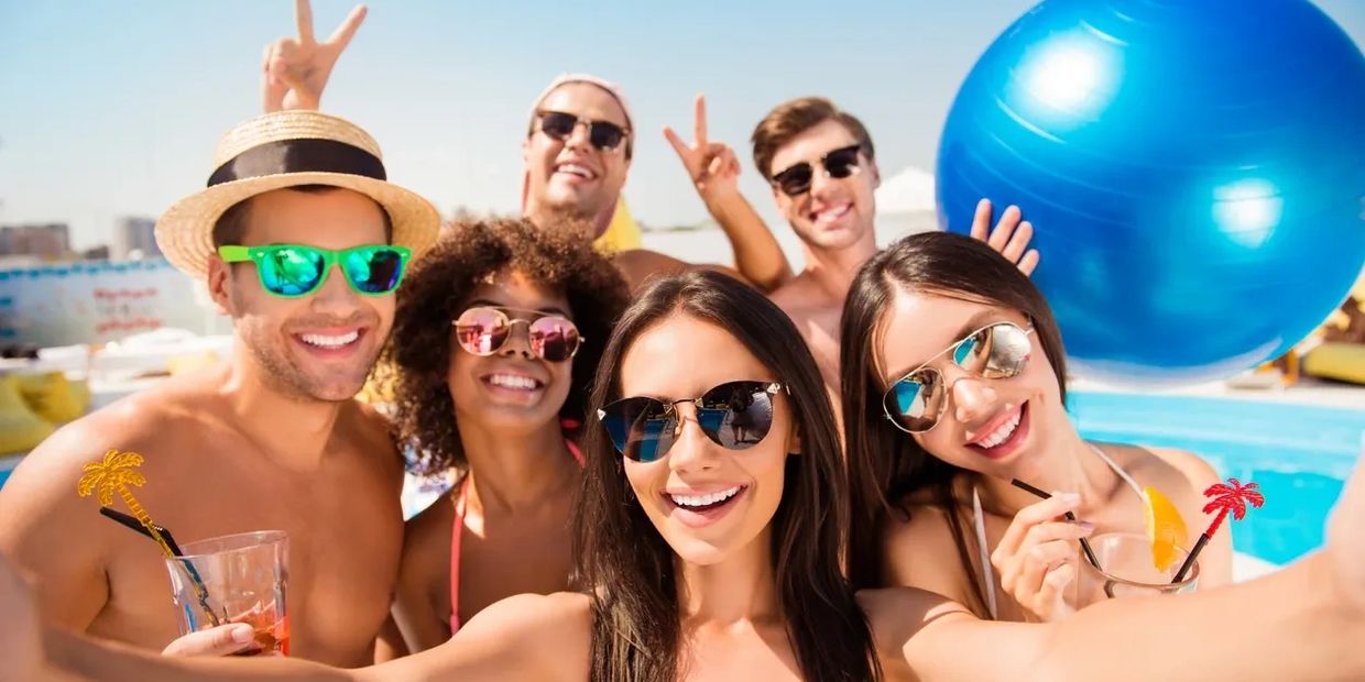 Group of friends taking a selfie by the pool on a sunny day.