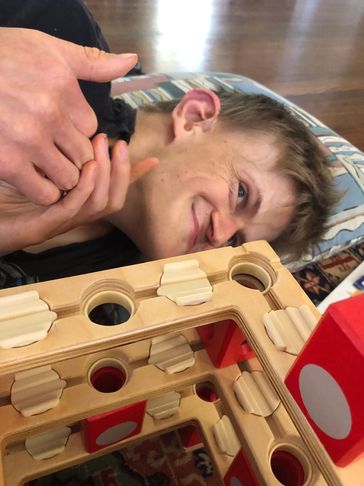 A young boy smiling while playing a wooden game.
