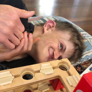 A young boy smiling while playing a wooden game.