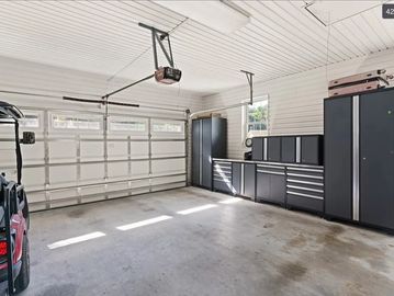 Organized empty garage with storage cabinets and windows.