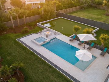 Modern backyard with pool, hot tub, and putting green.