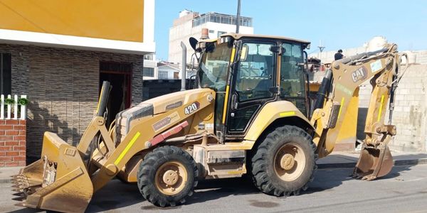 A yellow Caterpillar 420 backhoe loader parked on a street.