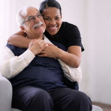 A young woman hugging an elderly man with smiles.