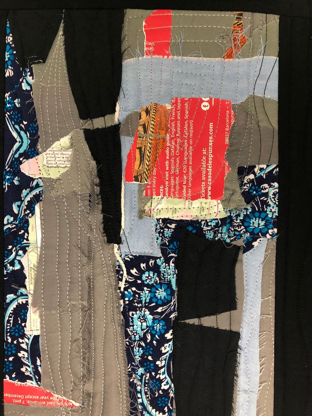 Abstract textile collage with layered fabric and printed text.