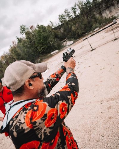 Man aiming gun outdoors at a shooting range.