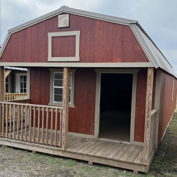Rustic wooden barn with a small porch and open door.