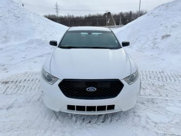 White Ford car parked in snowy surroundings with snowbanks.