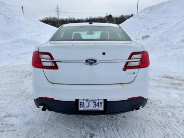 Rear view of a white Ford sedan parked on a snowy road.
