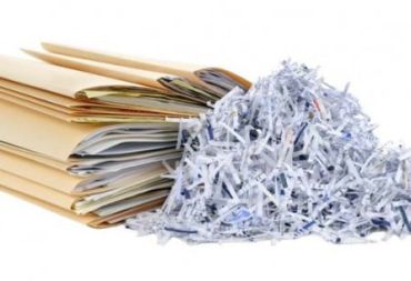 Stacks of folders next to shredded paper.