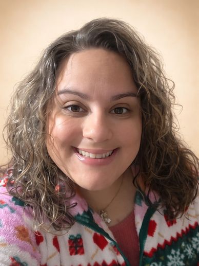Smiling woman in festive holiday sweater taking a selfie indoors.