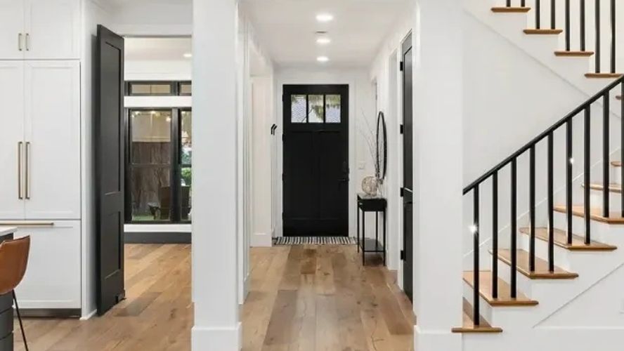 Modern kitchen with black and white design and wooden floors.