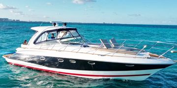 A sleek black and white yacht on clear blue ocean water under a sunny sky.