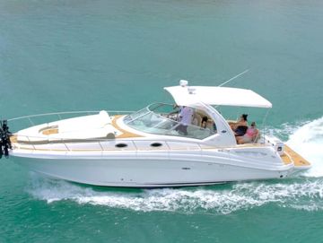 A white yacht cruising near a tropical beachfront resort.