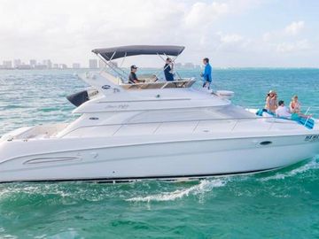 A white yacht cruising on turquoise waters with people enjoying the ride.