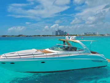 Luxury yacht cruising on clear turquoise waters near a tropical city.