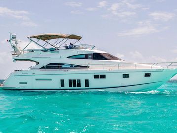 A white luxury yacht sailing on clear turquoise water under a partly cloudy sky.