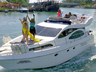 People enjoying a sunny day on a white yacht near a beach resort.