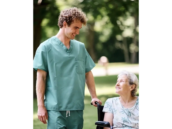 Male nurse with long term care patient walking through a park